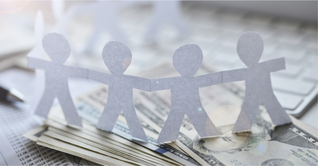 Paper cut outs of children holding hands on top of money.